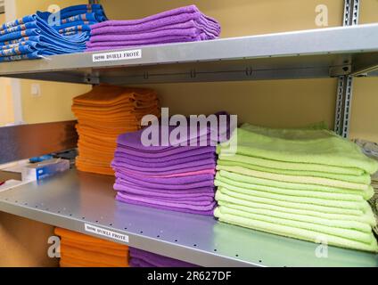 Serviettes souples en tissu éponge propres de différentes couleurs pliées, empilées dans un tas. Des piles de serviettes empilées sur les étagères de la buanderie. Banque D'Images