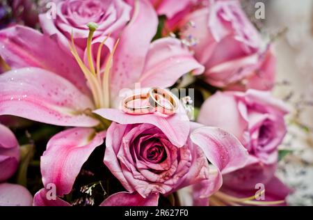 Image des anneaux de mariage sur nénuphars roses Banque D'Images