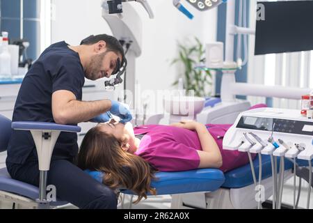 Le contrôle dentaire de la patiente dans la clinique moderne a concentré le dentiste dans les gants vérifiant les dents de la femme Banque D'Images
