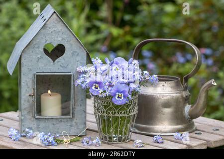 aménagement de jardin vintage avec bouquet de fleurs de violons bleus, cloches espagnoles et oubliez-moi pas des fleurs et lanterne de zinc Banque D'Images