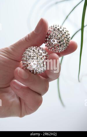 Billes magnétiques en métal argenté, outil à pointes pour le massage des mains. Outil de thérapie dans la main femelle d'âge moyen. Banque D'Images