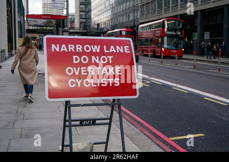 Londres, Royaume-Uni - 02 février 2019: Panneau rouge invitant à ne pas dépasser les cyclistes en raison de la route étroite dans le centre-ville animé, grand bâtiment Banque D'Images