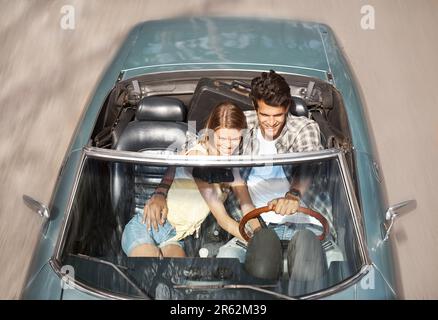 Conduire ensemble. Vue en grand angle d'un couple attrayant voyageant ensemble dans une voiture de sport à toit ouvert. Banque D'Images