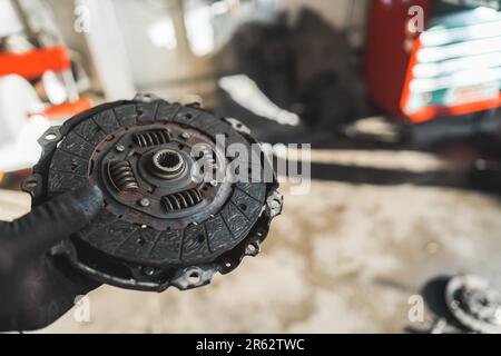 Mains de mécanicien tenant un ancien embrayage cassé à l'atelier de voiture. Photo de haute qualité Banque D'Images