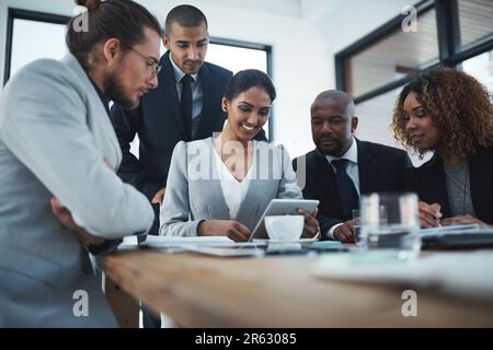 Découvrez ce que vos clients pensent de votre entreprise. un groupe d'hommes et de femmes d'affaires discutant de quelque chose sur une tablette numérique. Banque D'Images