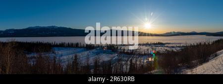 Drone, vue aérienne d'un coucher de soleil du nord du Canada avec un immense lac gelé et un ciel bleu, nuages partiels à distance. Prise le long de l'Alaska Highway Banque D'Images