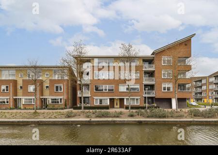 un complexe d'appartements sur le bord de l'eau avec des arbres et des bâtiments à l'avant - partie de la photo Banque D'Images