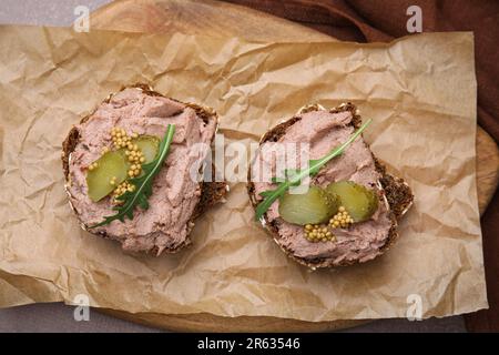 Délicieux sandwiches de livrewurst avec concombre mariné et moutarde sur table grise, vue de dessus Banque D'Images