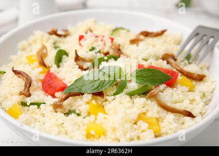 Bol de couscous délicieux avec légumes et basilic, gros plan Banque D'Images