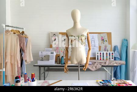 Mannequin avec tissus colorés dans la salle des créateurs de mode. Machine à coudre et divers articles liés à la couture sur la table. Banque D'Images