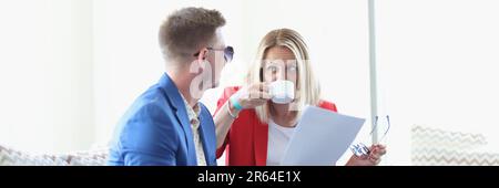 Un jeune couple discute autour d'une tasse de café dans un café et regarde à travers les documents d'affaires Banque D'Images