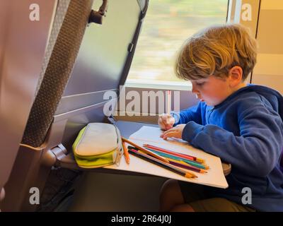 Enfant en train à grande vitesse tire et écrit dans le bloc-notes Banque D'Images