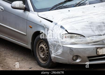 Une voiture en collision, un pare-chocs avant, un phare et un capot endommagés par du ruban adhésif Banque D'Images