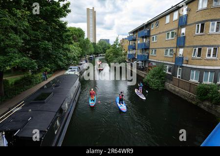 Londres - 05 21 2022 : bateau à voile et trois paddleboarders le long du canal de Grand Union Banque D'Images