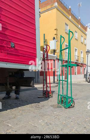 Camion semi-remorque déchargeant des marchandises au centre-ville. Il y a deux chariots à côté du véhicule Banque D'Images