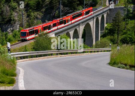 Grengiols, canton du Valais, Suisse - 27 mai 2023 : un train rouge passant sur le pont circulaire du viaduc au printemps. Banque D'Images