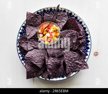 Une assiette de tortillas de maïs bleu avec un bol de salsa maison. Banque D'Images
