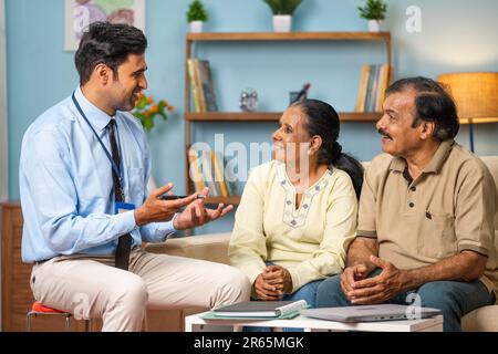 Banquier indien professionnel expliquant au sujet de la police d'assurance à un couple senior à la maison - concept de conseiller financier, expert d'affaires et Banque D'Images