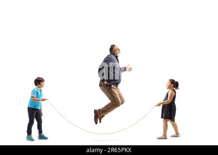 Prise de vue sur toute la longueur d'un homme mature sautant une corde avec des enfants isolés sur fond blanc Banque D'Images