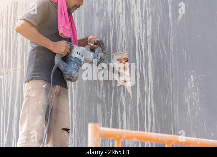 La destruction de la construction par les travailleurs. travailleur avec marteau brisant le plâtrage de mur intérieur Banque D'Images