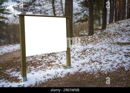 Vider le panneau d'affichage blanc dans le parc avec des taches de neige au sol. Banque D'Images