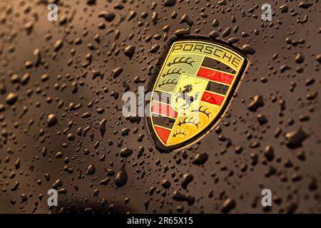 Masi, Italie, 7 juin 2023 : photo en gros plan d'une voiture noire présentant l'emblématique emblème Porsche et des gouttelettes d'eau. Banque D'Images