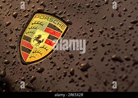 Masi, Italie, 7 juin 2023 : photo en gros plan d'une voiture noire présentant l'emblématique emblème Porsche et des gouttelettes d'eau. Banque D'Images