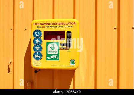 Défibrillateur jaune vital dans un boîtier monté sur un mur orange Banque D'Images