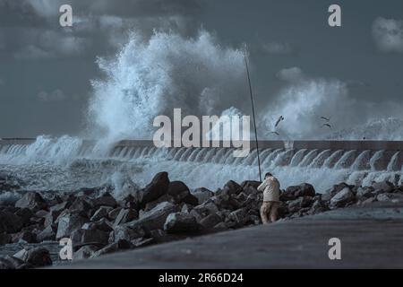 Porto, Portugal - 20 décembre 2015 : pêcheur sportif à l'embouchure du fleuve Douro pendant une forte tempête. Filtre infrarouge utilisé. Banque D'Images