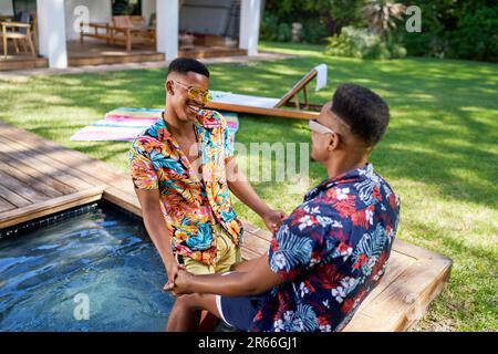 Un couple de hommes gay heureux tient les mains dans la piscine de l'arrière-cour Banque D'Images