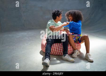 Portrait les jeunes amis enthousiastes s'embuent sur la chaise de sac de haricot Banque D'Images