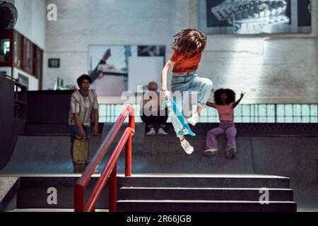 Jeune femme faisant une cascade de skateboard au parc de skateboard Banque D'Images