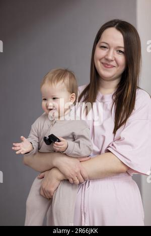 Jeune mère tenant son bébé dans les bras et souriant avec joie Banque D'Images