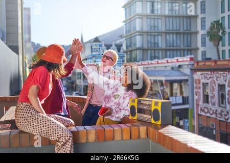 De jeunes amis heureux se hante sur le balcon ensoleillé de la ville Banque D'Images