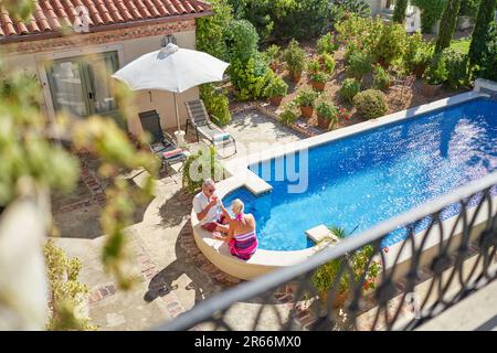 Couple senior se détendant dans une villa ensoleillée d'été au bord de la piscine Banque D'Images