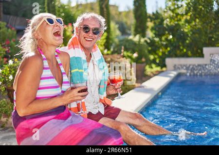 Portrait heureux, insouciant couple senior riant à la piscine d'été Banque D'Images