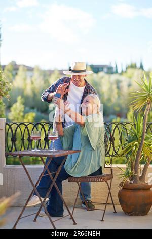 Joyeux couple senior discutant vidéo sur le balcon d'été Banque D'Images
