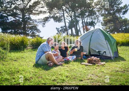 Bonne famille parlant et de boire de la tente extérieure au camping ensoleillé d'été Banque D'Images