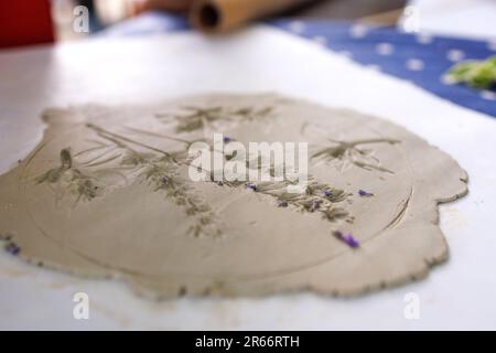 Création de pochoirs en céramique avec fleurs et feuilles de lavande et autres plantes en pressant sur la table Banque D'Images