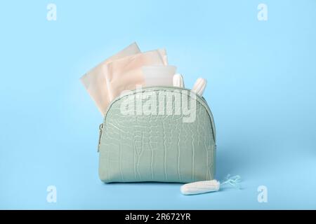 Sac cosmétique Lady's avec coupe menstruelle, coussinets et tampons sur fond bleu Banque D'Images