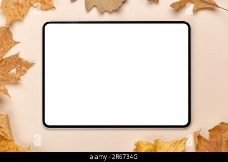 Tablette avec écran vierge sur une table entourée de feuilles d'automne nature, maquette parfaite Banque D'Images