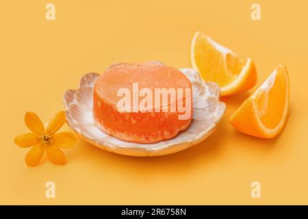 Plaque avec barre de shampooing solide, fleur et orange sur fond de couleur Banque D'Images