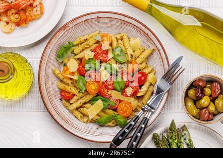 Une délicieuse assiette de pâtes italiennes ornée de tomates fraîches et de feuilles de basilic aromatiques. Pose à plat Banque D'Images