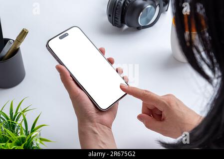Une femme tient un téléphone avec un écran isolé pour la présentation d'applications, symbolisant la connectivité professionnelle moderne dans un bureau Banque D'Images