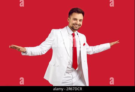 Cool gai gars dans blanc classique costume danse et se réjouit isolé sur fond rouge. Banque D'Images