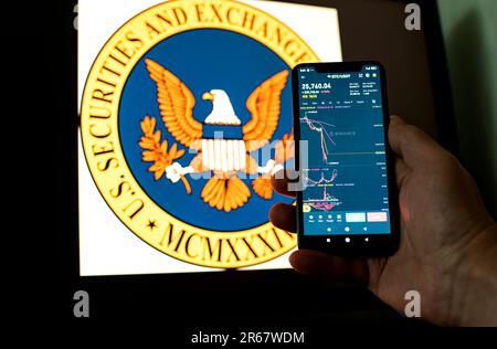 Kiev, Ukraine - 06 juin 2023: Man tient un smartphone avec le tableau de chute de Bitcoin sur Binance contre le fond le logo SEC. S.E.C. Accuse Binance Banque D'Images