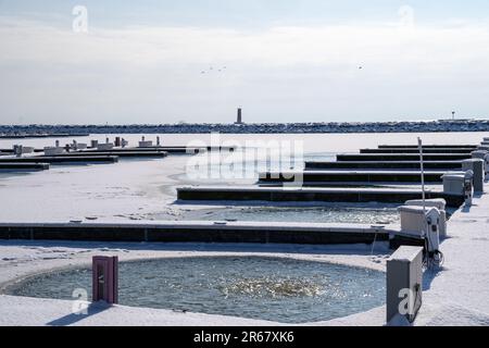 Vue sur les quais et les glissades de bateau sur le lac Michigan, avec le phare de Sheboygan au loin, pris en hiver dans le Wisconsin Banque D'Images