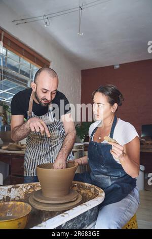 Personne ne connaît la poterie comme il connaît la poterie. un jeune homme et une jeune femme travaillant avec de l'argile dans un studio de poterie. Banque D'Images