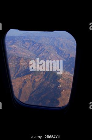 Vue aérienne de la chaîne de montagnes vue à travers une fenêtre d'avion pendant le coucher du soleil Banque D'Images