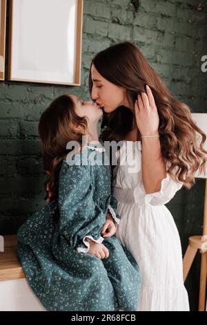 Fête des mères. Une jeune maman sensible embrasse sa petite fille adorable à la maison. Confiance, soutien et amour entre maman et enfant. Une famille aimante Banque D'Images